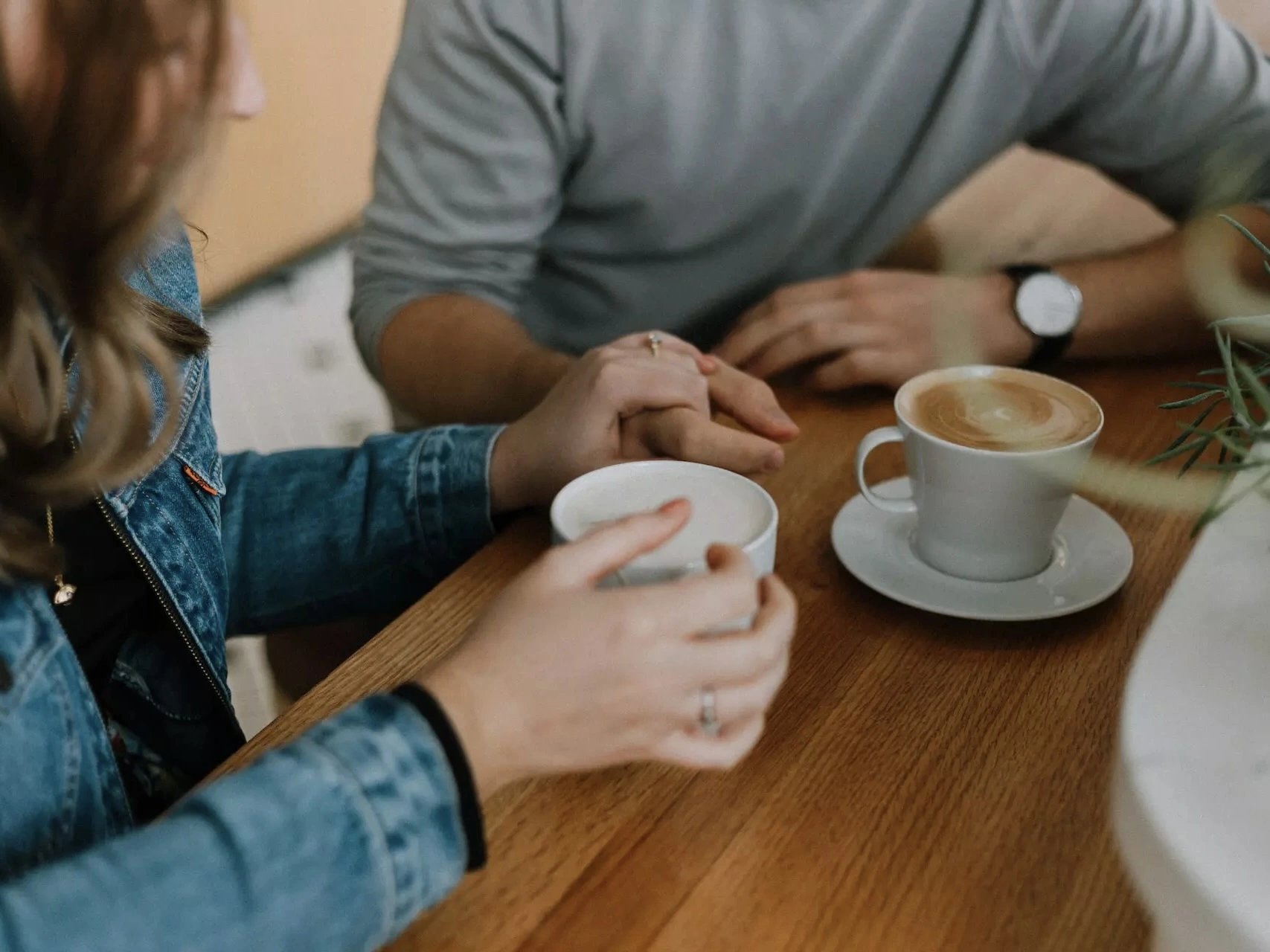 A couple holding hands and drinking coffee. 