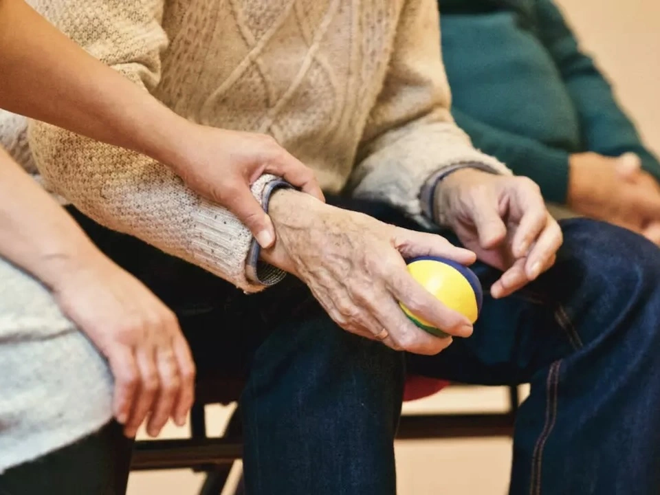 A nurse holds an elderlan mans hand. 