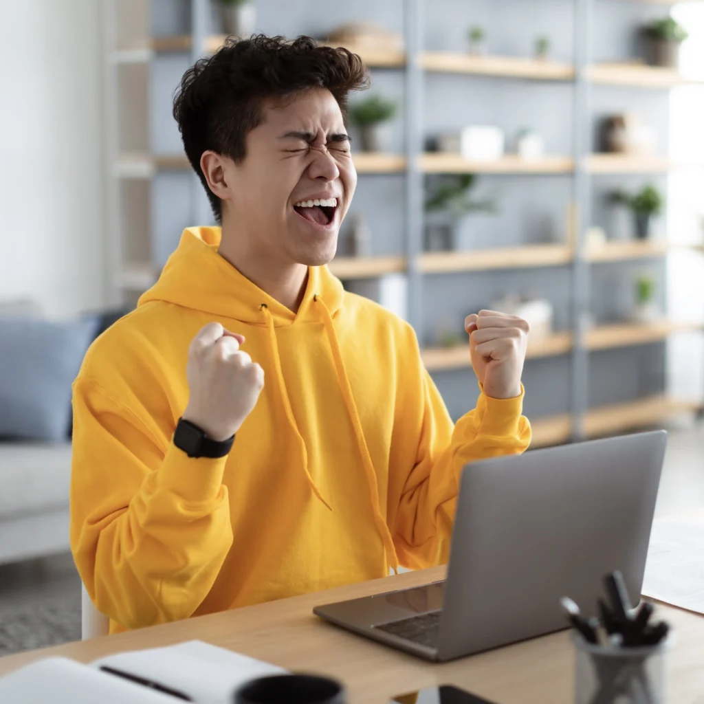 A man cheering while using a laptop.
