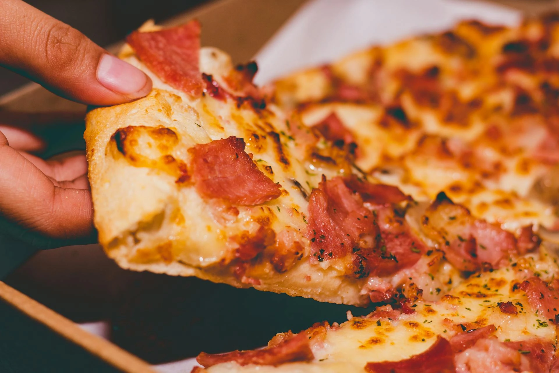 Someone taking a slice of pizza.