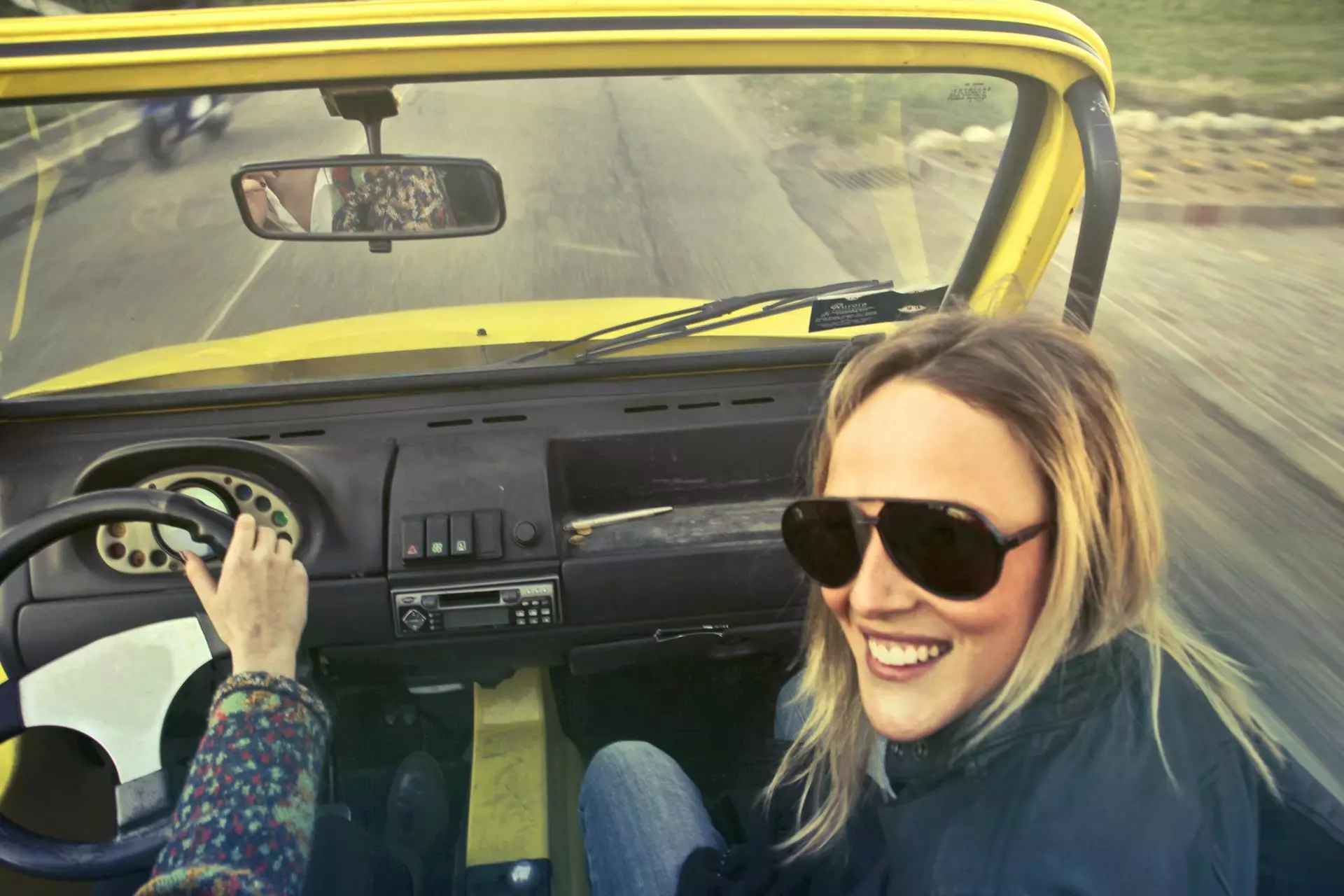Two people driving in an open-topped car.