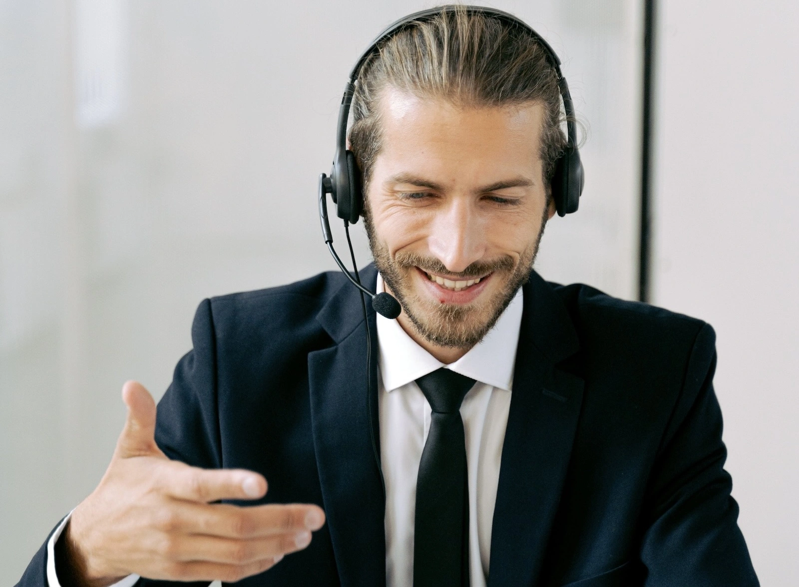 A smiling man in headphones is talking to someone on his laptop.