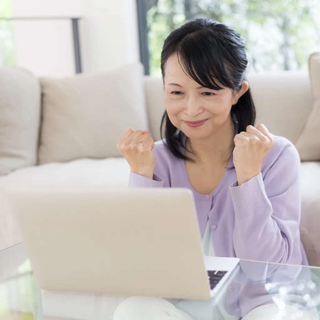 A woman gesturing happily while looking at a laptop. 
