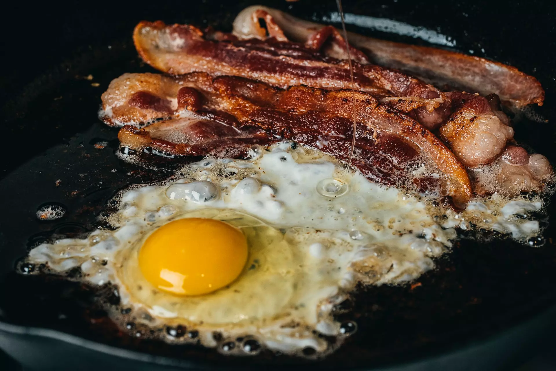 Bacon and eggs cooking in a hot pan.